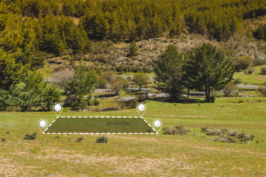 Marked land boundary with GPS location pins over grassy meadow and forested hillside